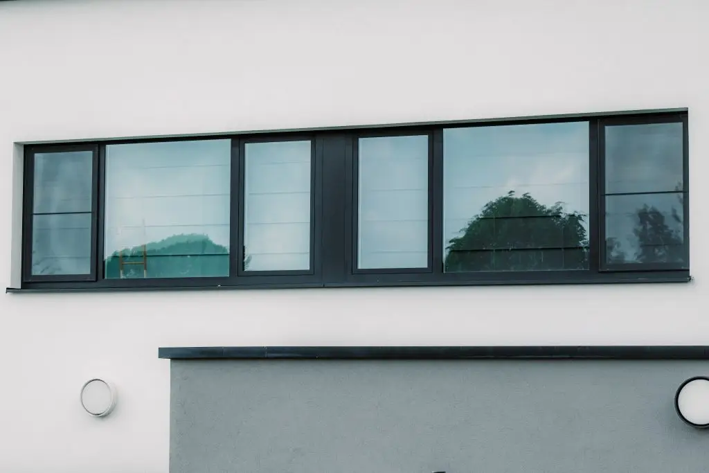 Façade moderne avec un bandeau de fenêtres et des châssis aluminium foncés et sur mesure