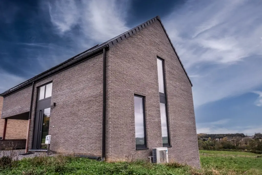 Maison en briques foncées avec de grands chassis en PVC noir sur mesure