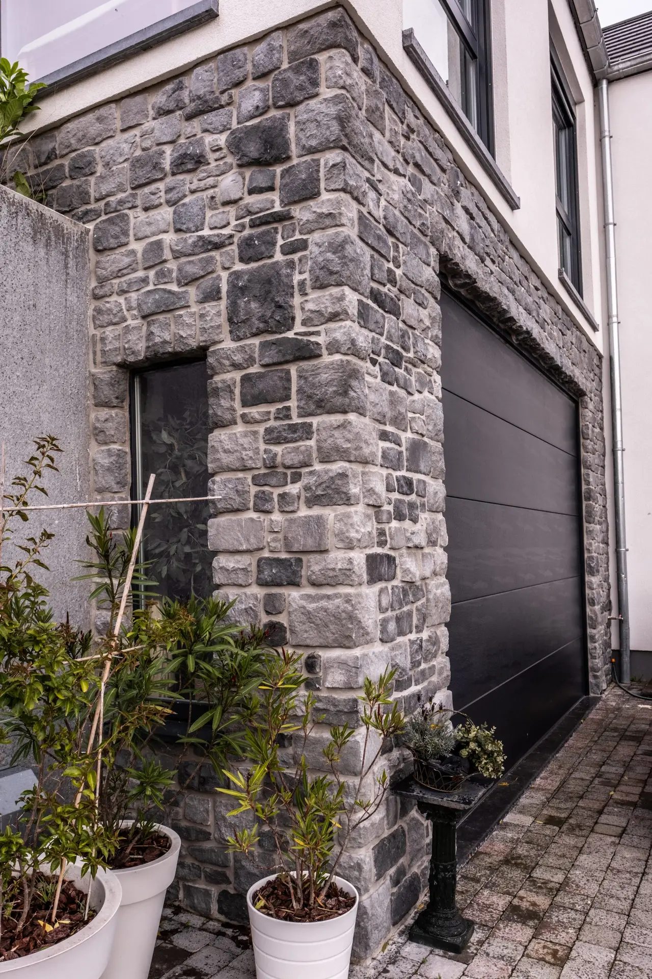 Porte de garage sectionnelle gris anthracite assortie au mur en pierre