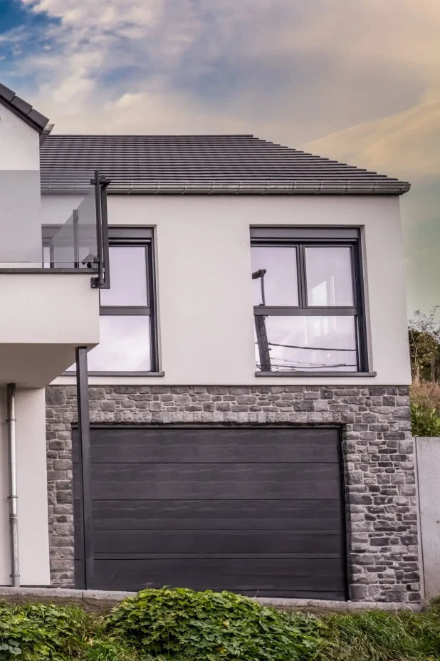 Maison en crépi blanc avec une grande porte de garage noire